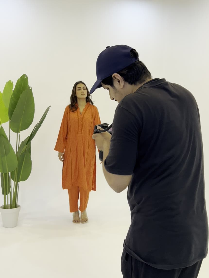 Behind the scenes — a photographer shooting a model on the studio cyclorama